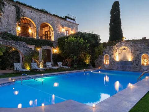 A pool with lights on in front of a house.