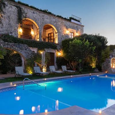 A pool with chairs and lights on the side of it